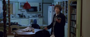 Movie still from “The End of the Tour” (2015), directed by James Ponsoldt – A man holding a cell phone in his hand; Medium shot, Over the shoulder angle