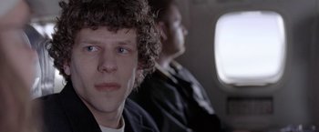 Movie still from “The End of the Tour” (2015), directed by James Ponsoldt – Two men sitting on a plane looking at the camera; Close Up shot, Over the shoulder angle