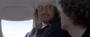 Movie still from “The End of the Tour” (2015), directed by James Ponsoldt – A person wearing glasses and a hat; Close Up shot, Over the shoulder angle