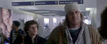Movie still from “The End of the Tour” (2015), directed by James Ponsoldt – Two people standing next to each other in an airport; Close Up shot, Over the shoulder angle