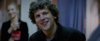 Movie still from “The End of the Tour” (2015), directed by James Ponsoldt – A person with curly hair smiling; Close Up shot, Over the shoulder angle