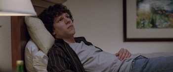 Movie still from “The End of the Tour” (2015), directed by James Ponsoldt – A man sitting on a couch with his arms crossed; Medium shot, High angle