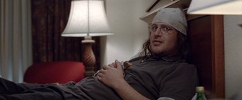 Movie still from “The End of the Tour” (2015), directed by James Ponsoldt – A man with a head band on sitting on a couch; Close Up shot, High angle