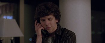 Movie still from “The End of the Tour” (2015), directed by James Ponsoldt – A man talking on a cell phone while sitting down; Close Up shot, Over the shoulder angle