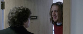Movie still from “The End of the Tour” (2015), directed by James Ponsoldt – A man with long hair talking to another man in a room; Close Up shot, Over the shoulder angle