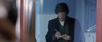 Movie still from “The End of the Tour” (2015), directed by James Ponsoldt – A man writing on a piece of paper while holding a pen; Medium shot, Over the shoulder angle