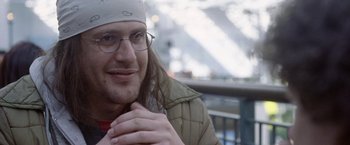 Movie still from “The End of the Tour” (2015), directed by James Ponsoldt – A person wearing glasses and a hat; Close Up shot, Over the shoulder angle