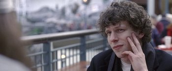 Movie still from “The End of the Tour” (2015), directed by James Ponsoldt – A man with curly hair sitting at an outdoor table; Close Up shot, Over the shoulder angle