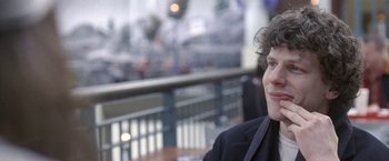 Movie still from “The End of the Tour” (2015), directed by James Ponsoldt – A woman sitting at a table in front of a railing; Close Up shot, Over the shoulder angle