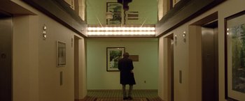 Movie still from “The End of the Tour” (2015), directed by James Ponsoldt – A woman standing in a hallway looking at a painting; Wide shot, Low angle
