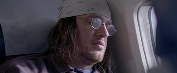 Movie still from “The End of the Tour” (2015), directed by James Ponsoldt – A person wearing glasses and a hat; Close Up shot, Low angle