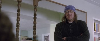 Movie still from “The End of the Tour” (2015), directed by James Ponsoldt – A man standing next to a wooden pole in a living room; Medium shot, Low angle