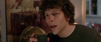 Movie still from “The End of the Tour” (2015), directed by James Ponsoldt – A man holding a camera in a room; Close Up shot, Over the shoulder angle