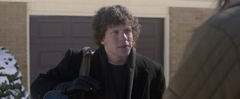 Movie still from “The End of the Tour” (2015), directed by James Ponsoldt – A man with curly hair holding a brown bag; Close Up shot, Over the shoulder angle