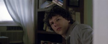 Movie still from “The End of the Tour” (2015), directed by James Ponsoldt – A man with curly black hair is looking at the camera; Close Up shot, Over the shoulder angle