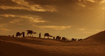 Movie still from “The English Patient” (1996), directed by Anthony Minghella – A group of people walking on top of a sand dune; Extreme Wide shot, High angle