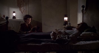 Movie still from “The English Patient” (1996), directed by Anthony Minghella – A woman sitting on a bed looking at a book; Wide shot, High angle
