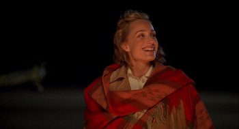 Movie still from “The English Patient” (1996), directed by Anthony Minghella – A woman in a red and brown shawl smiling; Close Up shot, Over the shoulder angle
