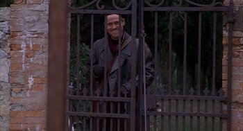 Movie still from “The English Patient” (1996), directed by Anthony Minghella – A man standing in front of an iron gate; Medium shot, Over the shoulder angle