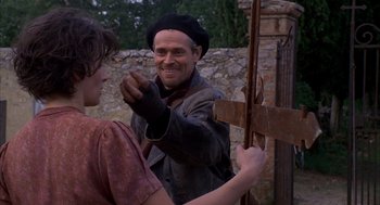 Movie still from “The English Patient” (1996), directed by Anthony Minghella – A man in a hat and a jacket holding a wooden stick; Medium shot, Over the shoulder angle