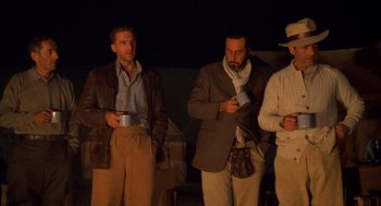 Movie still from “The English Patient” (1996), directed by Anthony Minghella – A group of men standing next to each other holding coffee cups; Medium shot, Low angle