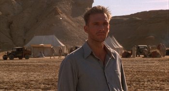 Movie still from “The English Patient” (1996), directed by Anthony Minghella – A man standing in front of some tents in the desert; Close Up shot, Low angle