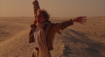 Movie still from “The English Patient” (1996), directed by Anthony Minghella – A woman in the desert with her arms outstreched; Medium shot, Low angle