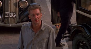 Movie still from “The English Patient” (1996), directed by Anthony Minghella – A man standing on the side of the street; Close Up shot, Over the shoulder angle