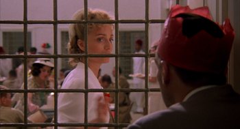 Movie still from “The English Patient” (1996), directed by Anthony Minghella – A woman in white shirt and tie in a jail cell; Close Up shot, Over the shoulder angle