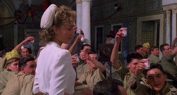 Movie still from “The English Patient” (1996), directed by Anthony Minghella – A group of men and women drinking beer at an event; Medium shot, Over the shoulder angle