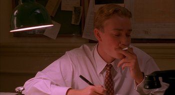 Movie still from “The English Patient” (1996), directed by Anthony Minghella – A man in a white shirt and a red tie is writing; Close Up shot, Low angle