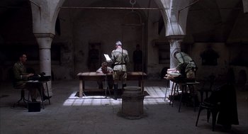 Movie still from “The English Patient” (1996), directed by Anthony Minghella – An old man sitting at a table reading a book; Wide shot, High angle