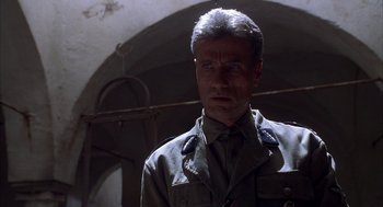 Movie still from “The English Patient” (1996), directed by Anthony Minghella – A man in a military uniform standing next to a wall; Close Up shot, Low angle