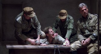 Movie still from “The English Patient” (1996), directed by Anthony Minghella – A man being held down on a table by two men in military uniforms; Medium shot, High angle