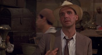 Movie still from “The English Patient” (1996), directed by Anthony Minghella – A man in a suit and a hat is looking up; Close Up shot, Over the shoulder angle