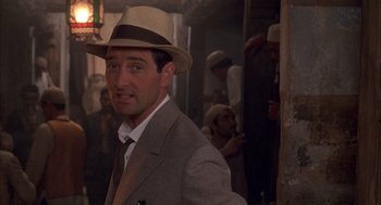 Movie still from “The English Patient” (1996), directed by Anthony Minghella – A man wearing a hat and a suit and tie; Close Up shot, Over the shoulder angle