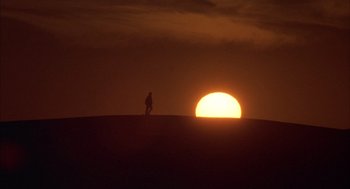 Movie still from “The English Patient” (1996), directed by Anthony Minghella – A person standing on top of a hill at sunset; Extreme Wide shot, Low angle