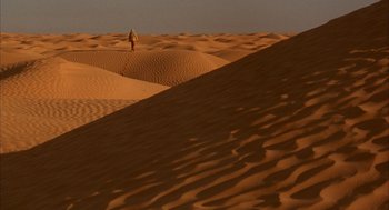Movie still from “The English Patient” (1996), directed by Anthony Minghella – A person standing on top of a sand dune in the desert; Extreme Wide shot, High angle