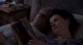 Movie still from “The English Patient” (1996), directed by Anthony Minghella – A man and a woman laying in a bed reading a book; Close Up shot, High angle
