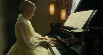 Movie still from “The Fabelmans” (2022), directed by Steven Spielberg – A woman in a yellow dress playing a piano; Medium shot, Low angle