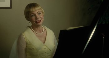 Movie still from “The Fabelmans” (2022), directed by Steven Spielberg – A woman in a white dress and pearls standing in front of a piano; Close Up shot, Over the shoulder angle