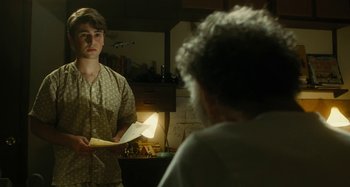 Movie still from “The Fabelmans” (2022), directed by Steven Spielberg – A young man holding an object in front of an older woman; Medium shot, Over the shoulder angle
