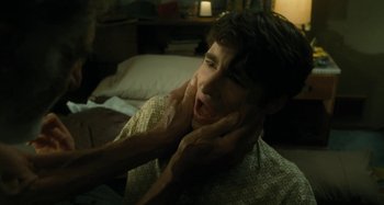 Movie still from “The Fabelmans” (2022), directed by Steven Spielberg – A young man holding his face in a dark room; Close Up shot, Over the shoulder angle
