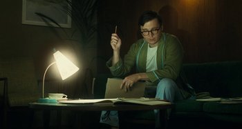 Movie still from “The Fabelmans” (2022), directed by Steven Spielberg – A man sitting at a table with a laptop; Medium shot, Low angle