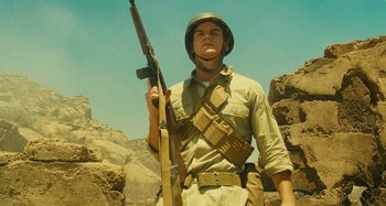 Movie still from “The Fabelmans” (2022), directed by Steven Spielberg – A man holding a rifle while standing on top of a hill; Medium shot, Low angle