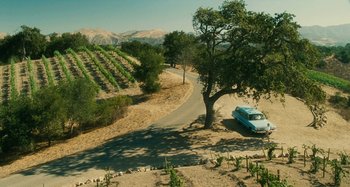 Movie still from “The Fabelmans” (2022), directed by Steven Spielberg – A van parked on the side of a road near a tree; Extreme Wide shot, High angle