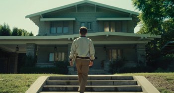 Movie still from “The Fabelmans” (2022), directed by Steven Spielberg – A man walking down the steps of a house; Wide shot, Low angle