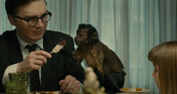 Movie still from “The Fabelmans” (2022), directed by Steven Spielberg – A man and a monkey are eating at a table; Medium shot, Over the shoulder angle