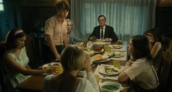 Movie still from “The Fabelmans” (2022), directed by Steven Spielberg – A group of people sitting at a table with plates of food on it; Medium shot, Over the shoulder angle