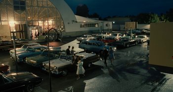 Movie still from “The Fabelmans” (2022), directed by Steven Spielberg – A group of people standing next to a bunch of old cars; Extreme Wide shot, High angle
